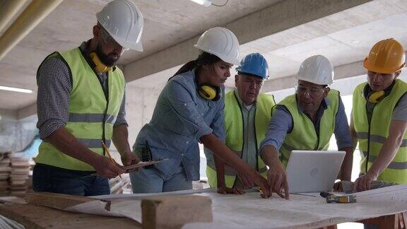 女建筑师在建筑工地向她的团队分配任务边说边指着图纸