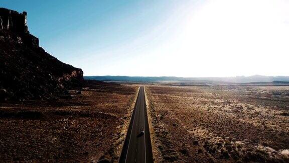 无人机拍摄的惊人的沙漠荒野与巨大的岩石山和汽车在美国高速公路上