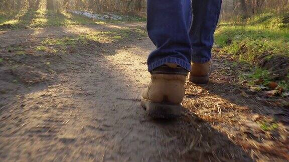 低视野的男性腿在靴子走在森林的一条小路上