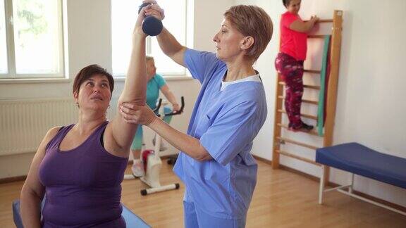 一位理疗师协助一位女病人做肩部运动