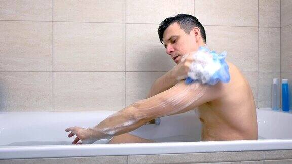 男人坐在浴缸里用沐浴露洗身体