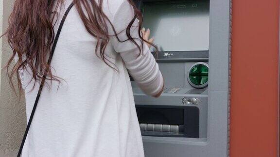 一位黑发年轻女子站在自动取款机前