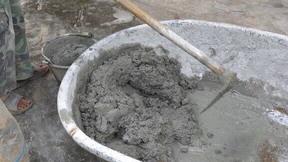工人在托盘中搅拌用于施工的水泥建筑工人把水和沙子放在混凝土上搅拌水泥