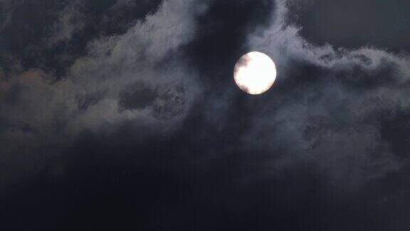 快速延时拍摄的满月在夜幕笼罩后从云中移动经过的场景黑烟遮住了月亮阴森的环境神秘的多云天空为恐怖电影的背景