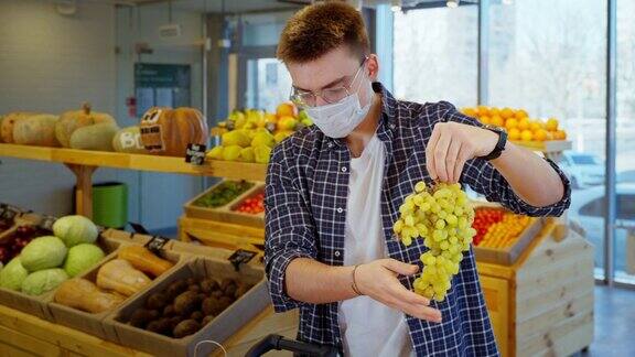 戴口罩的男子在超市买葡萄男顾客在疫情中购物
