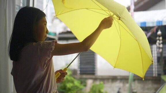 亚洲女学生在雨天使用黄色雨伞生活方式概念