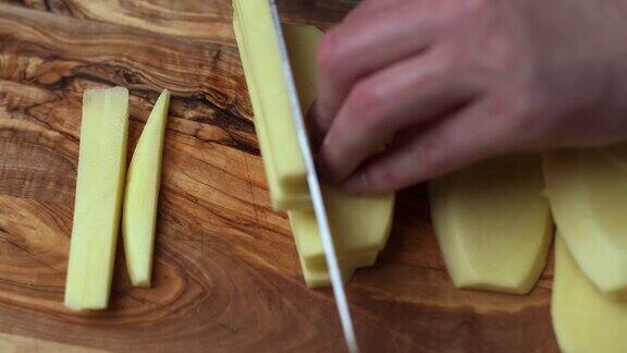把大土豆切成楔形准备炸薯条在木板上切土豆一个女人的手切土豆