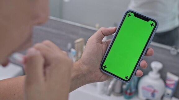 一名男子在浴室刷牙并使用色度键智能手机