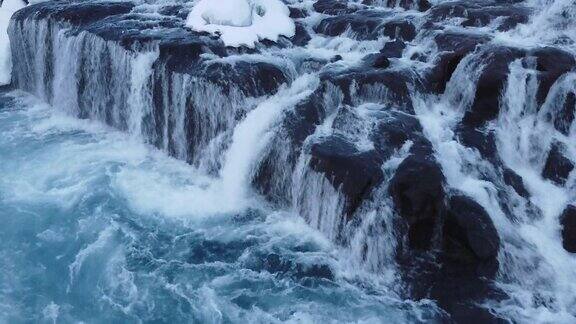 冬天的瀑布冰冷的山河纯净的蓝色冰川水冰岛鸟瞰图中神奇的户外雪景