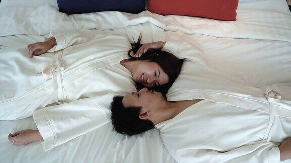 4K慢镜头拍摄相爱的亚洲情侣在豪华酒店卧室躺在床上的浪漫时刻生活方式和休闲概念