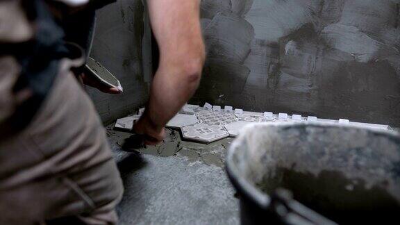 男工人在浴室地板上安装瓷砖