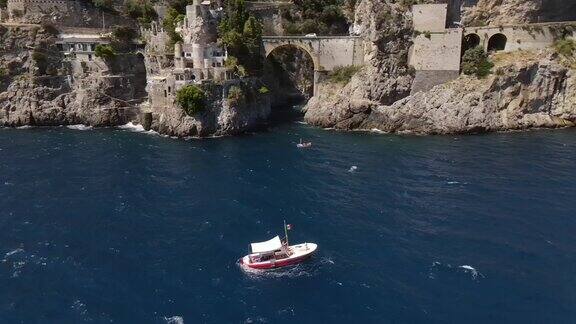 一艘红船的航拍视频背景是阿马尔菲海岸Furora峡湾的石拱桥
