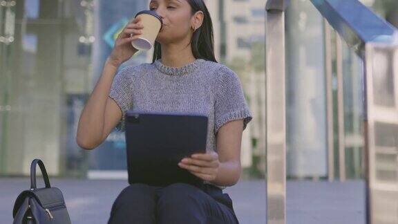 一个年轻的女商人一边喝咖啡一边用数字平板电脑