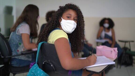 一个十几岁的女孩戴着面具在学校学习的肖像