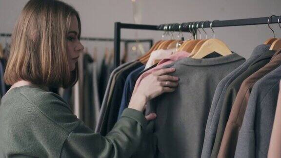 时尚的年轻女子在服装店挑选外套