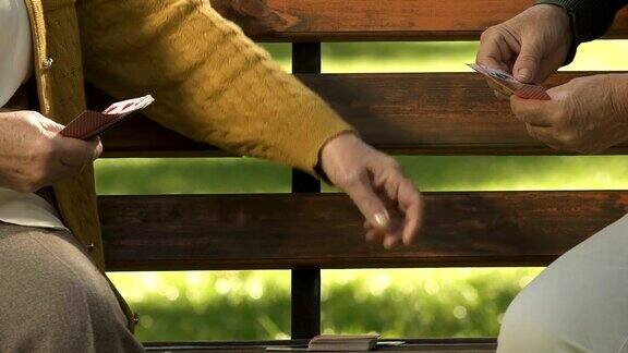 两个退休女性在公园长椅上打牌退休爱好友谊乐趣