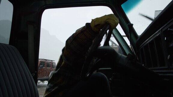 一个白种人在他三十多岁的胡子爬进他的卡车在一个雪天的冬天山里