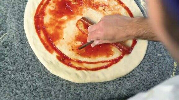 厨师用勺子在披萨面团上涂番茄酱传统的比萨餐厅食物的视频特写镜头股票视频