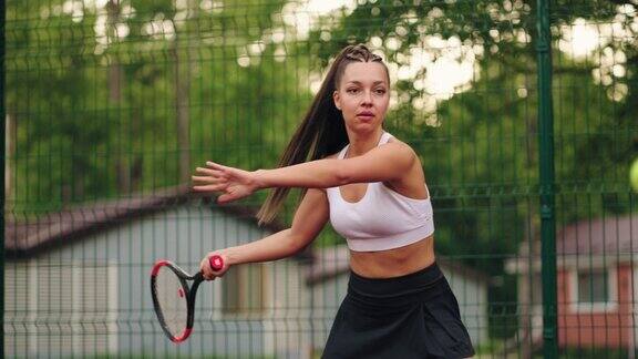 女网球初学者在夏天的球场上训练慢动作投篮