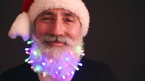 一位穿着黑色t恤、头戴圣诞老人帽的大胡子老人看着镜头开心地摇着头