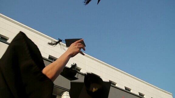 快乐的学生们穿着长袍把学位帽抛向空中教育、毕业与人理念-