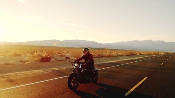 快乐的人骑着老式黑色摩托车在沙漠公路上