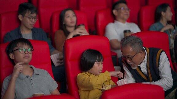 一位活跃的亚洲华人老人和他的孙辈们喜欢在电影院看电影