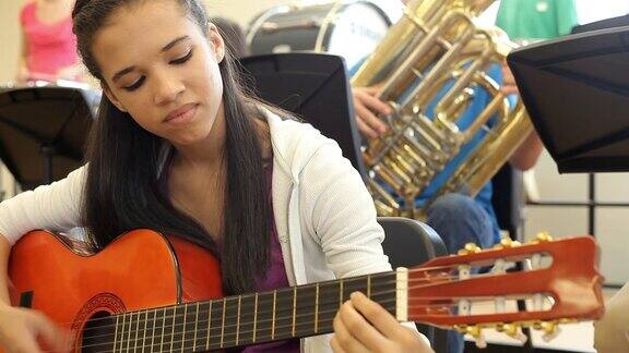 在高中管弦乐团演奏吉他的女学生