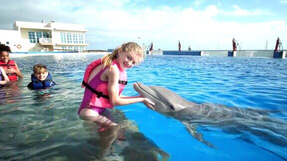 孩子和教练在水中女孩亲吻海豚