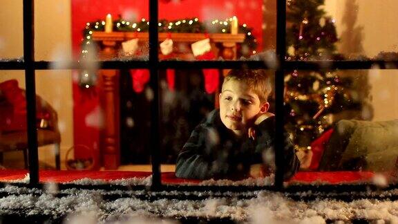男孩透过窗户看雪-圣诞节