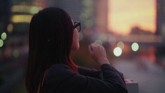年轻的女商人带着智能眼镜在市中心拍摄日落照片