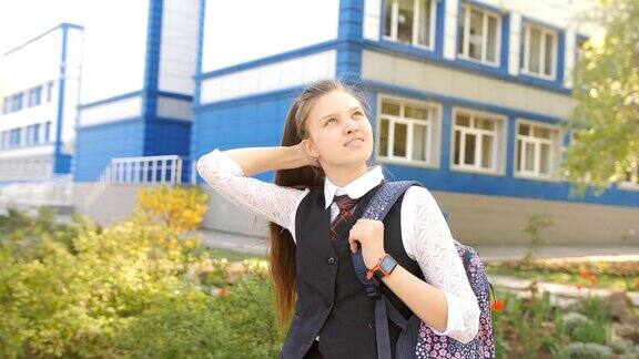 一个背着书包的少女在学校附近的肖像少女直发站在学校附近