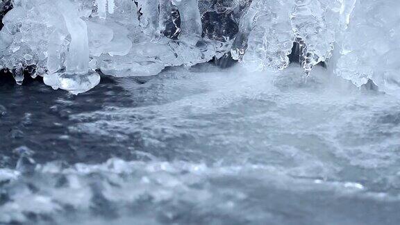 有冰和冰柱的冬季瀑布在寒冷季节有冰的河上流动的水