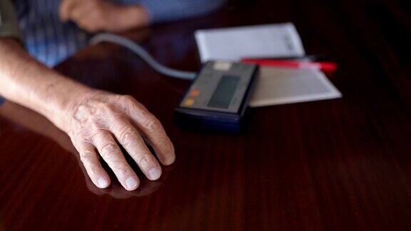 老人双手起皱用老式医用血压计测量血压和心跳脉搏用电子数字压力表检查高血压和低血压上了年纪的