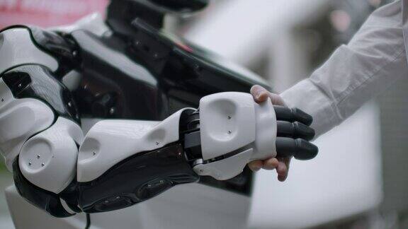 人与现代人工智能技术的互动走近科学家的男性手摇机械臂机器人和人类的手一起握手会见和问候朋友