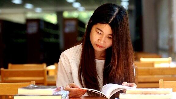 年轻的女学生坐在图书馆里看书