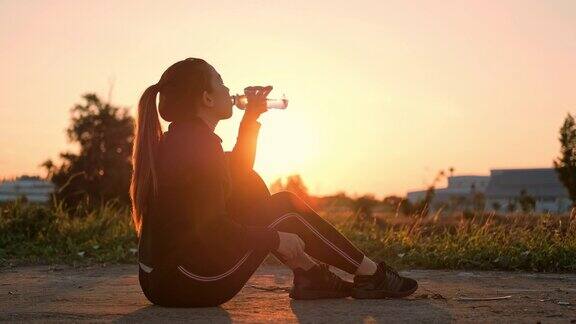 妇女在日落时间跑步后喝水