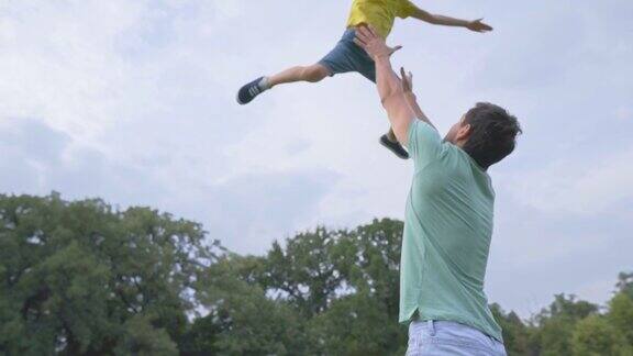 父亲和他的儿子在公园里玩耍把他扔到空中