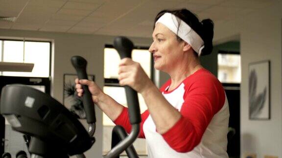 有吸引力的白种女人在训练机器上锻炼看起来很开心在健身中心中年健身和积极运动