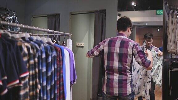 亚洲华人男性手拿男装衬衫在服装店尝试选择正确的一件购物