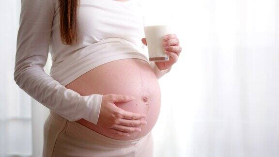 快乐的孕妇喝一杯新鲜的牛奶健康的钙茶点