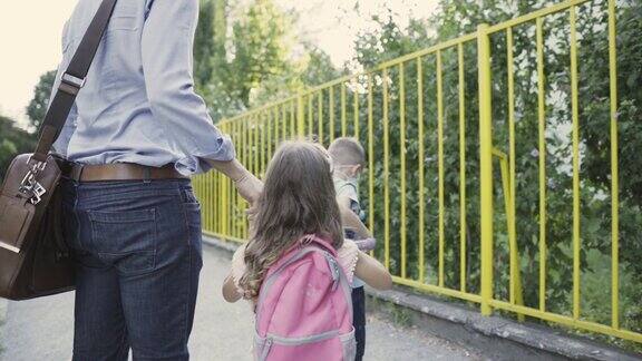 在去学校的路上父亲抱着戴着口罩的儿子和女儿