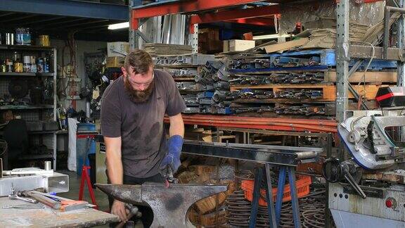 年轻的工匠铁匠使用传统的铁砧和锻造