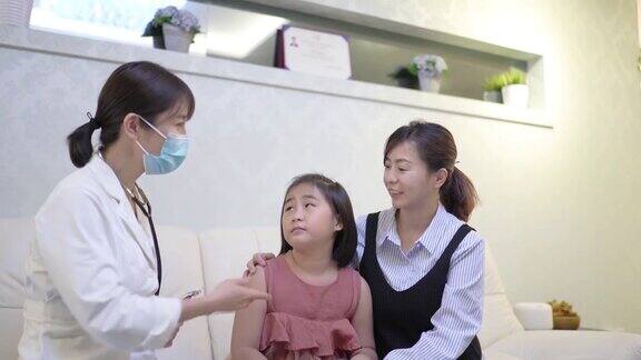 亚洲女医生戴着口罩用听诊器听女孩的心跳在医院的办公室