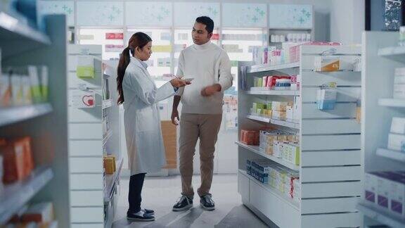 药店:女性亚洲药剂师帮助印度男性客户与推荐并建议购买药物药物维生素现代药店货架与保健产品