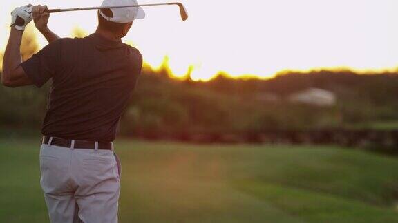男性白人高尔夫球手在日落练习挥杆