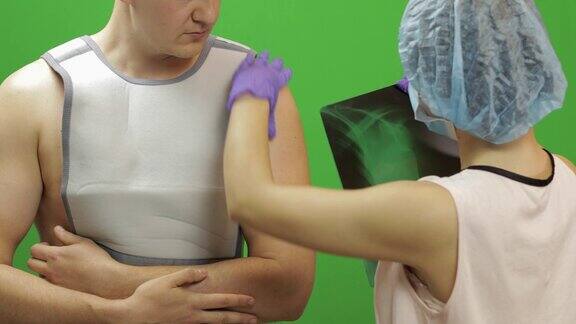 肩膀受伤的男人护士检查x射线肩部固定绷带
