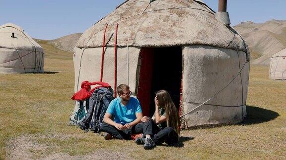 年轻的男女背包客早上在吉尔吉斯斯坦的蒙古包营地相遇
