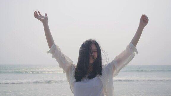 肖像美丽的年轻亚洲女人走在沙滩上享受生活快乐旅行自由放松人的生活方式4K慢镜头电影镜头