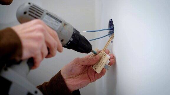 在室内维修过程中电线工人使用螺丝将电线连接到电源插座上